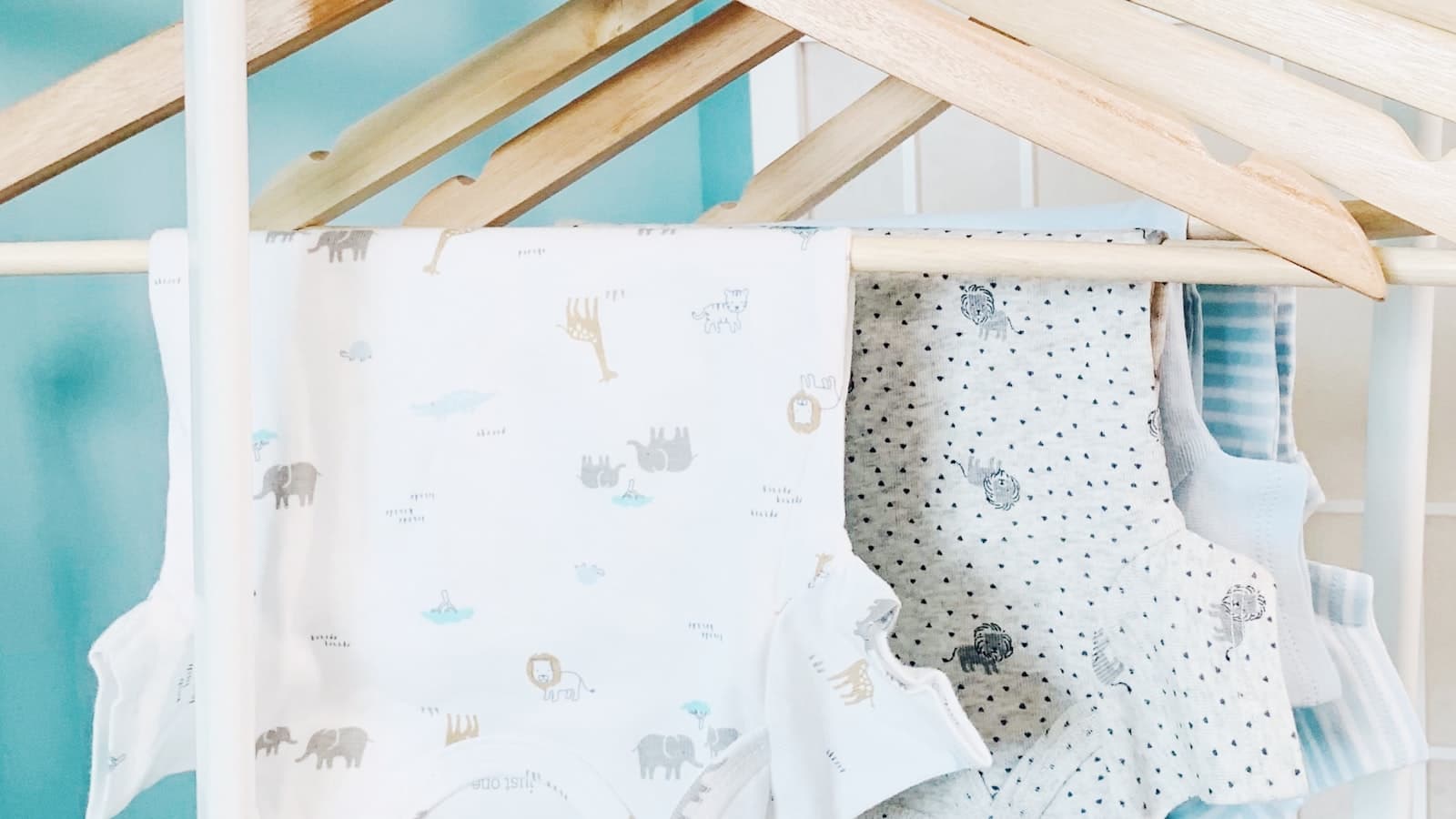 Baby onesies with animal prints hanging on wooden hangers