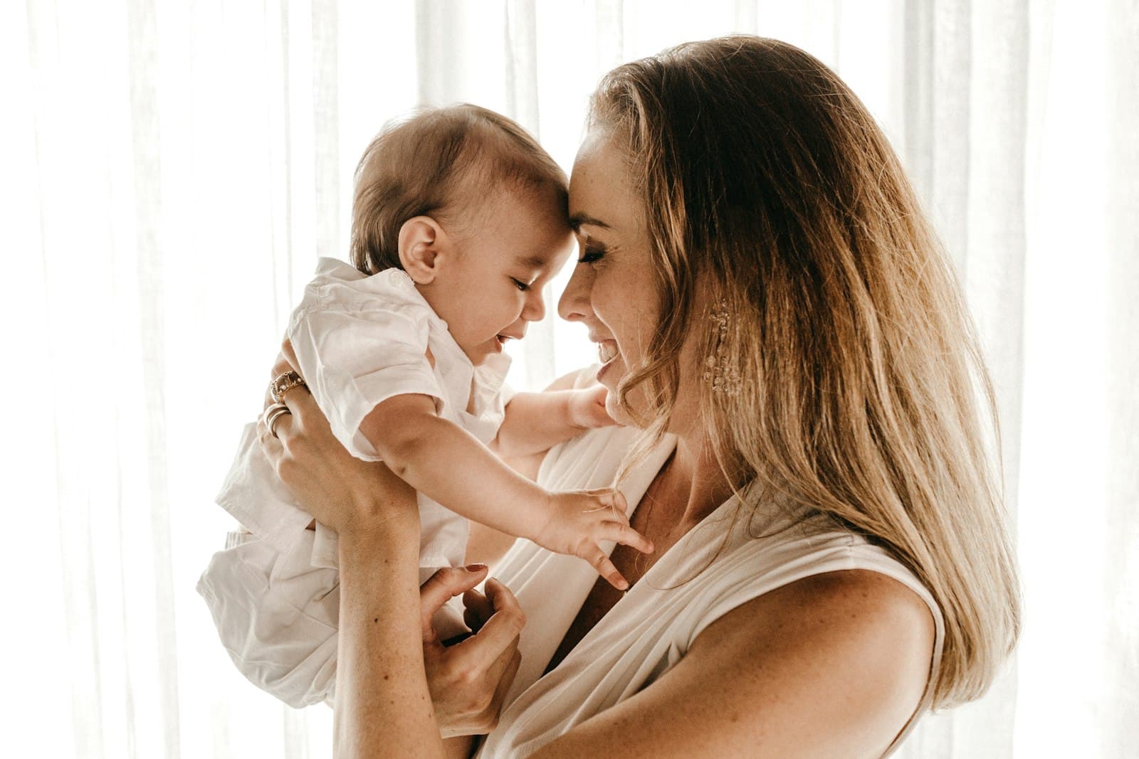 A mother holding her laughing baby, foreheads together