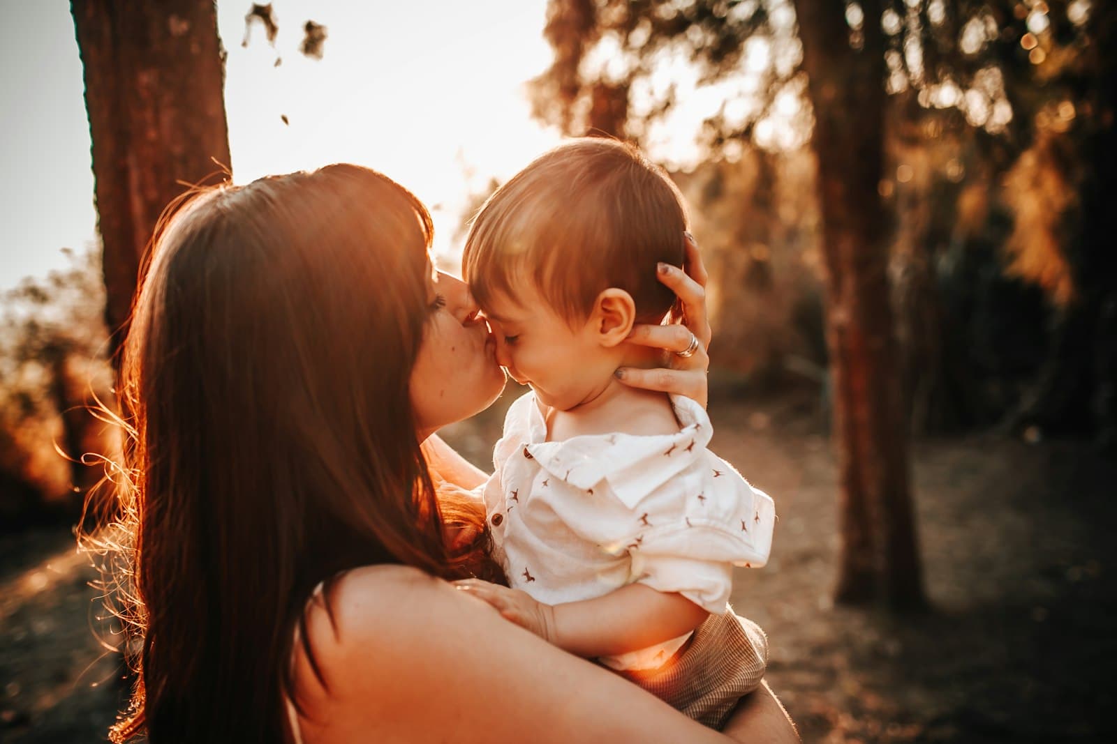 A parent laughing with their toddler outdoors at golden hour